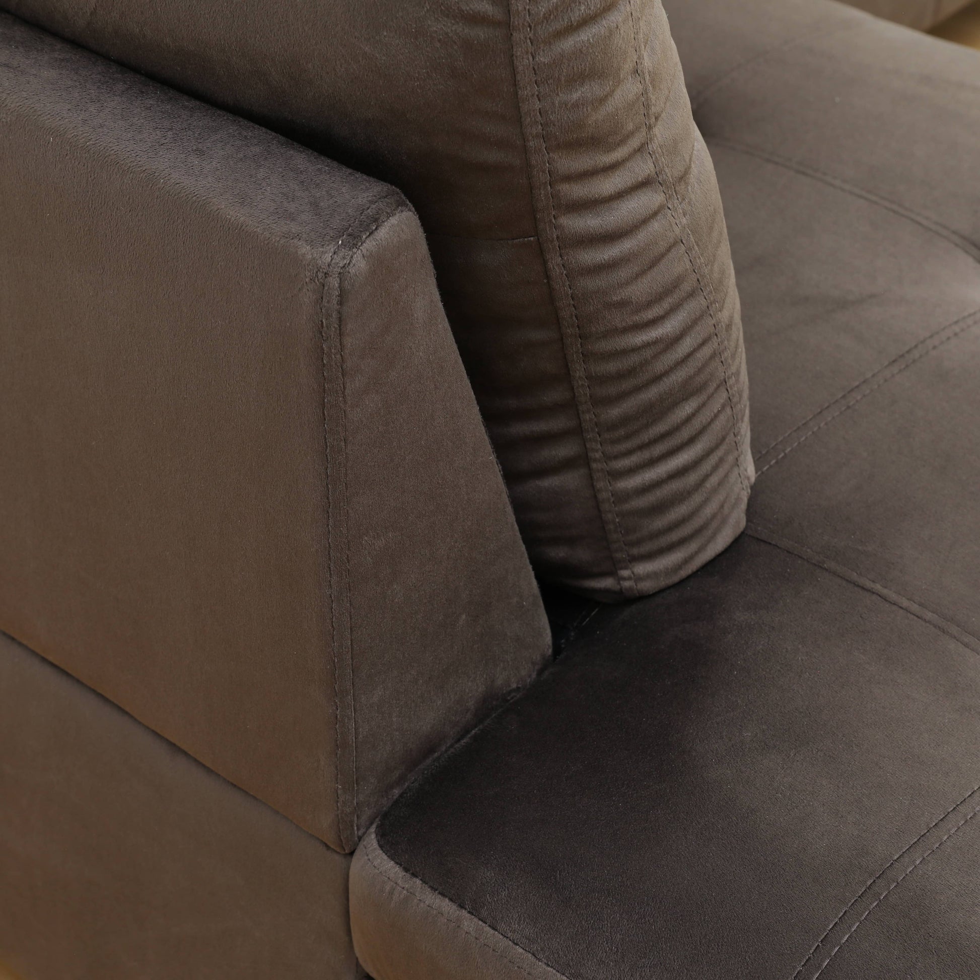 Closeup of plush brown velvet sofa armrest with intricate stitching details
