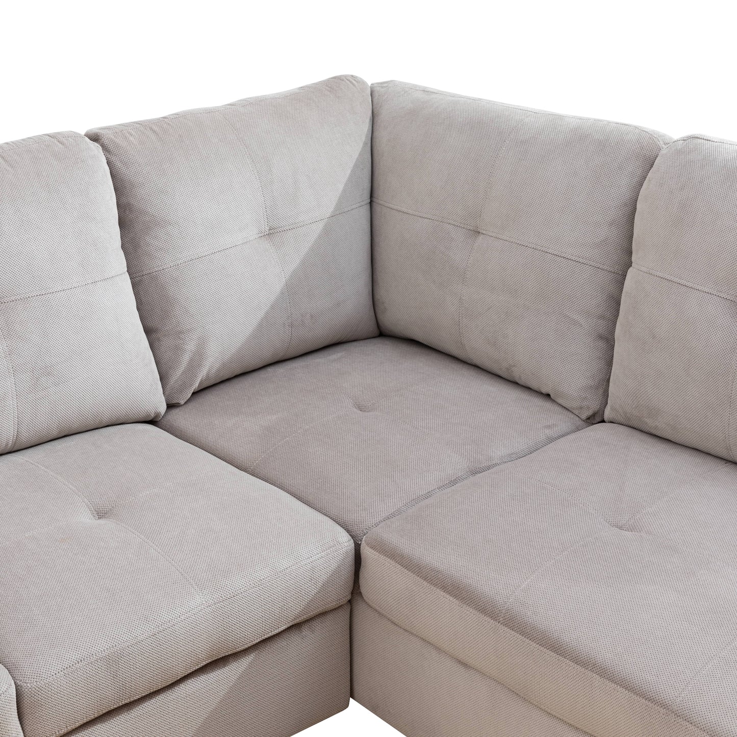 Closeup of a textured grey fabric sectional sofa with tufted cushions