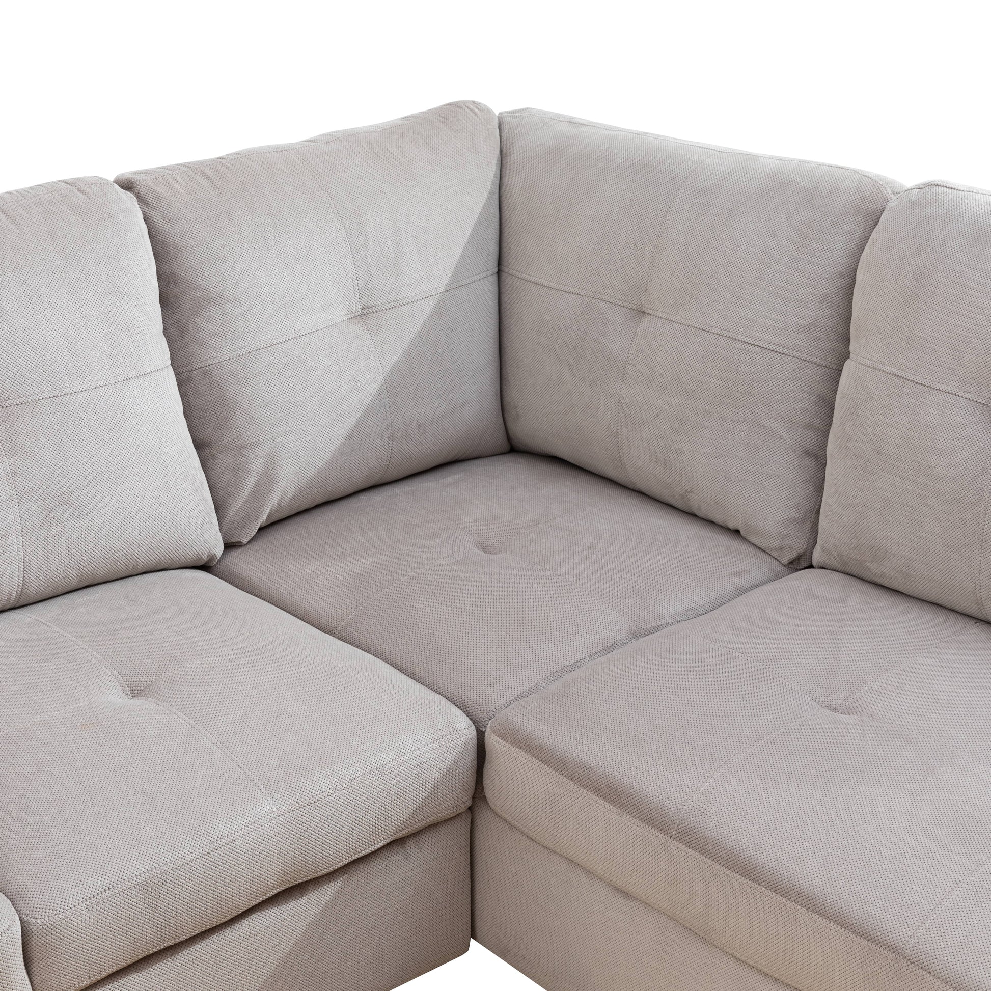 Closeup of a textured grey fabric sectional sofa with tufted cushions