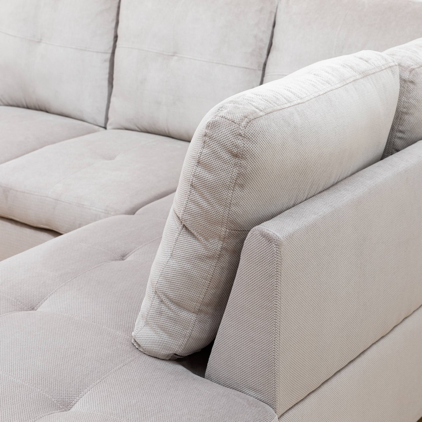 Closeup of plush beige fabric sectional sofa with tufted seat cushions