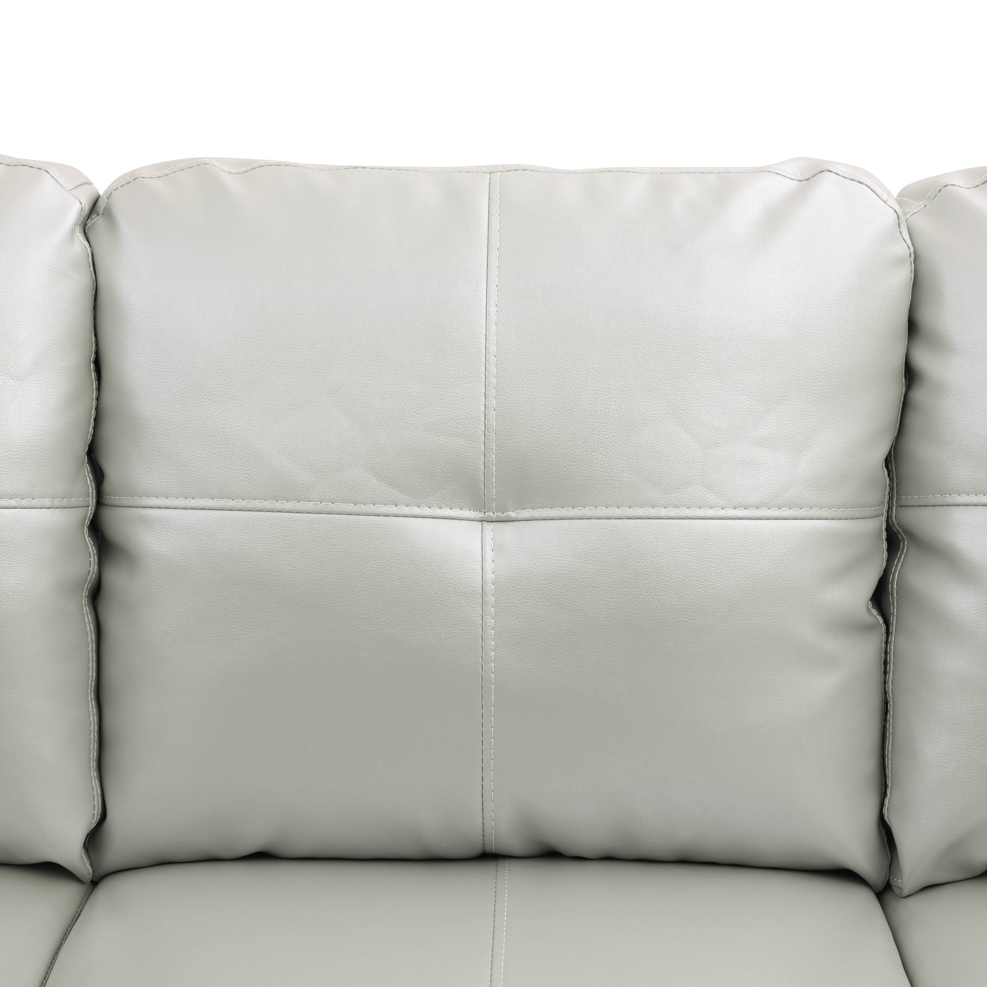 Closeup of a plush light grey faux leather sofa with stitched diamond pattern