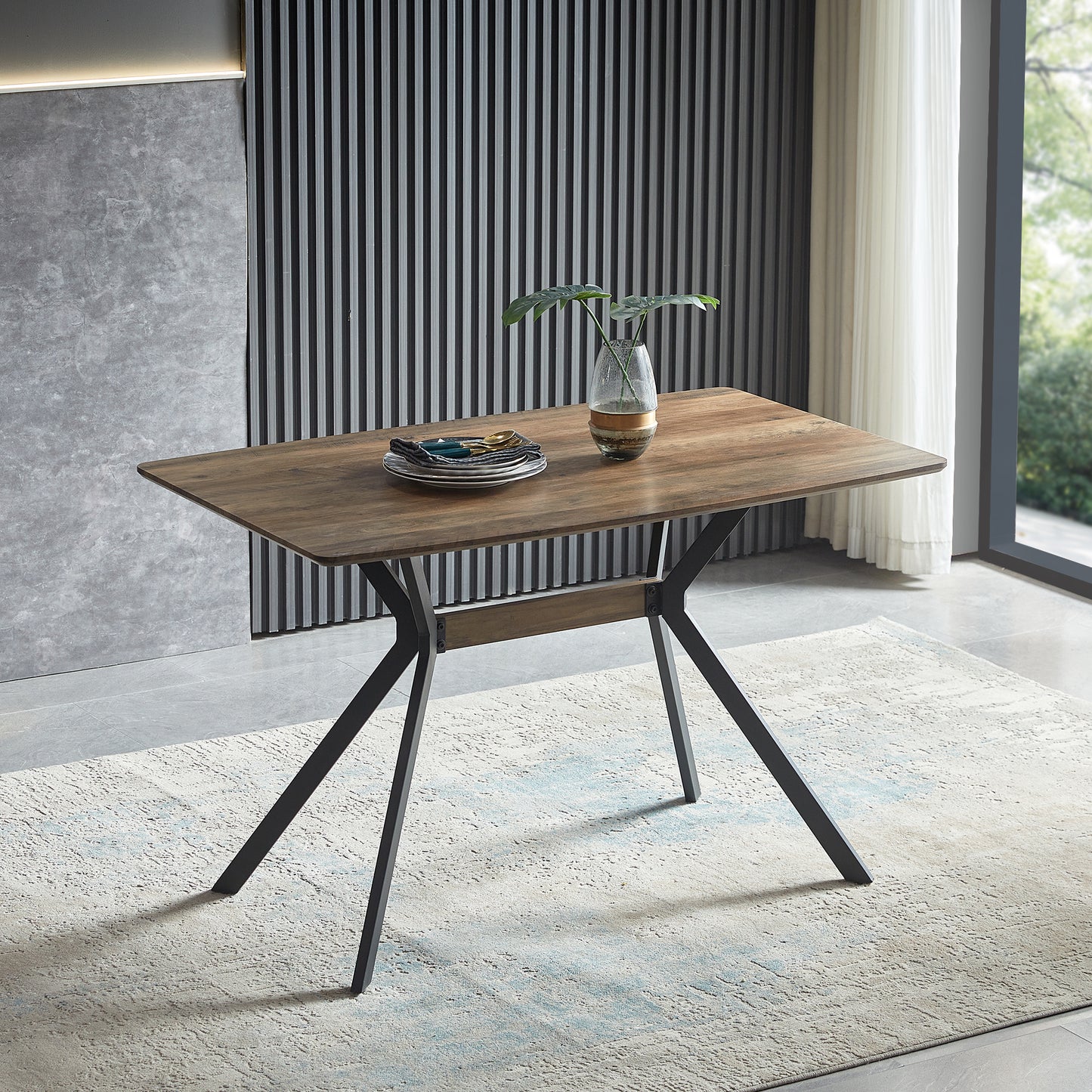 Wooden dining table with black metal legs and stack of plates