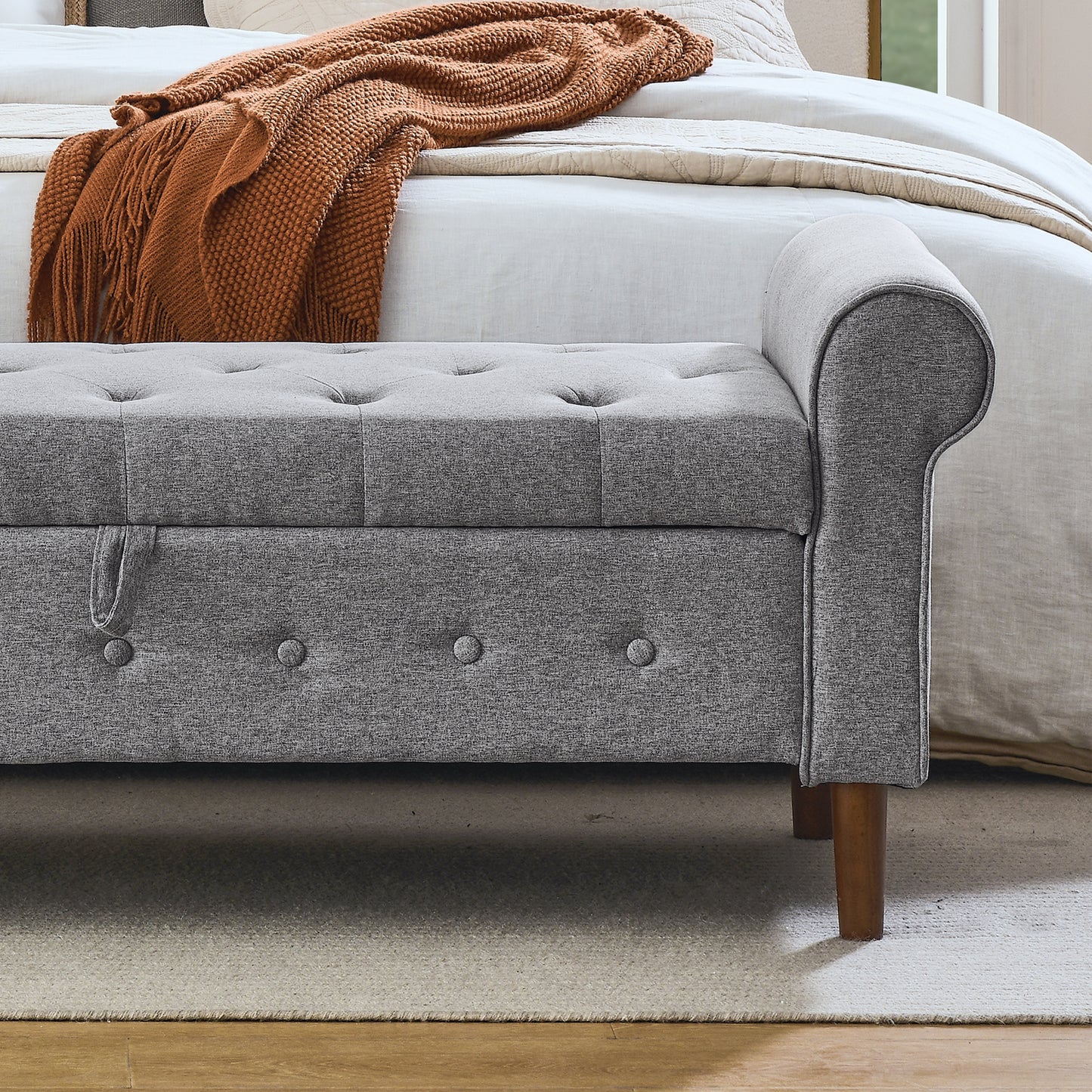 Gray upholstered storage bench with tufted top and wooden legs