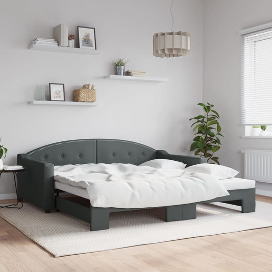 Dark gray upholstered sofa bed with tufted backrest and white bedding