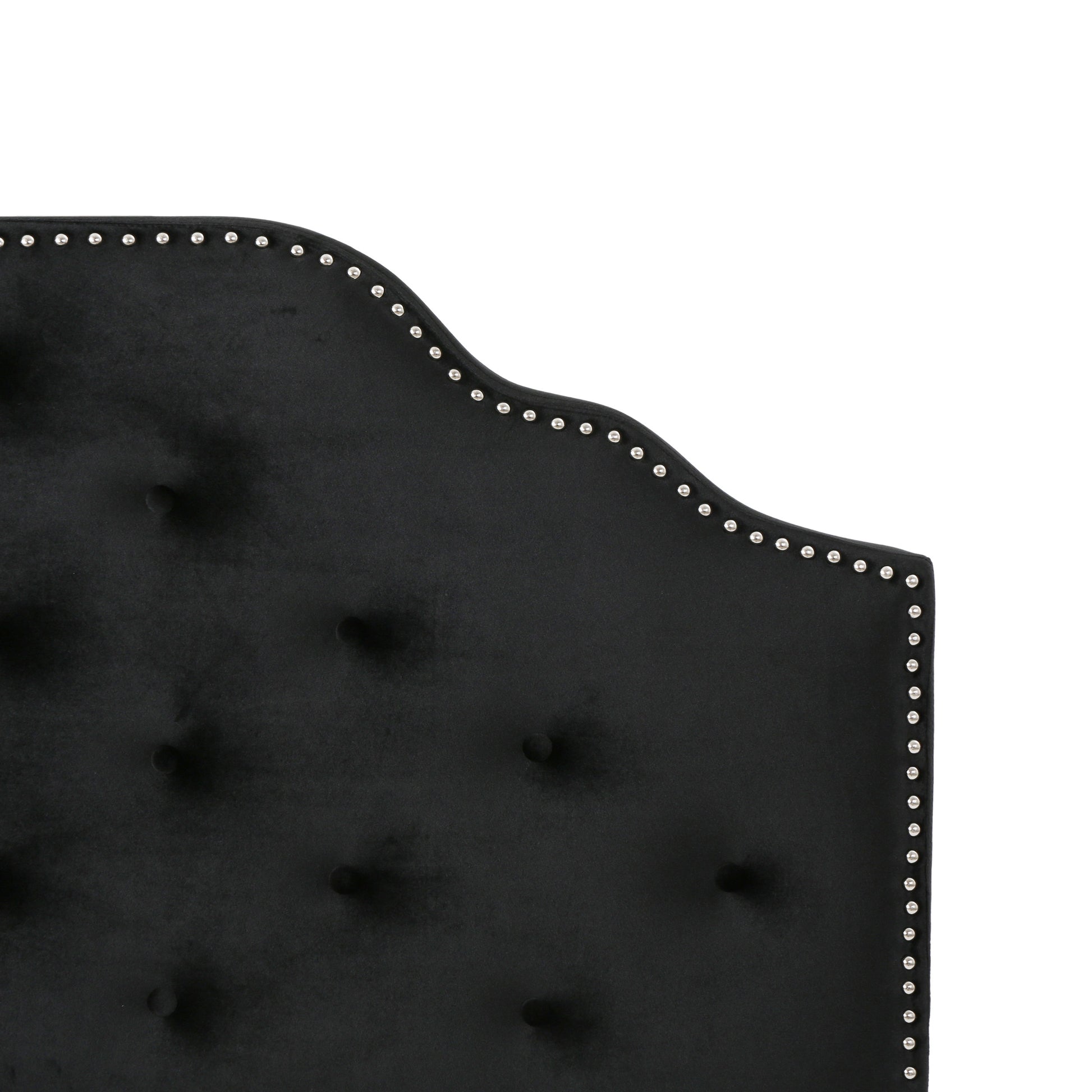 Closeup of black velvet headboard with diamond tufting and silver nailhead trim