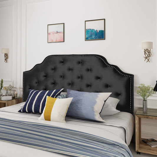 Black velvet tufted headboard with silver nailhead trim providing elegant bedroom style
