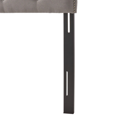 Tufted grey fabric headboard with silver nailhead trim and black metal support leg