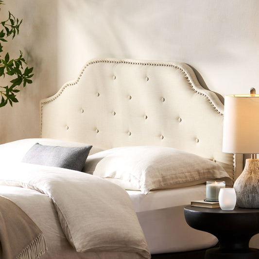Cream upholstered headboard with button tufting and silver nailhead trim
