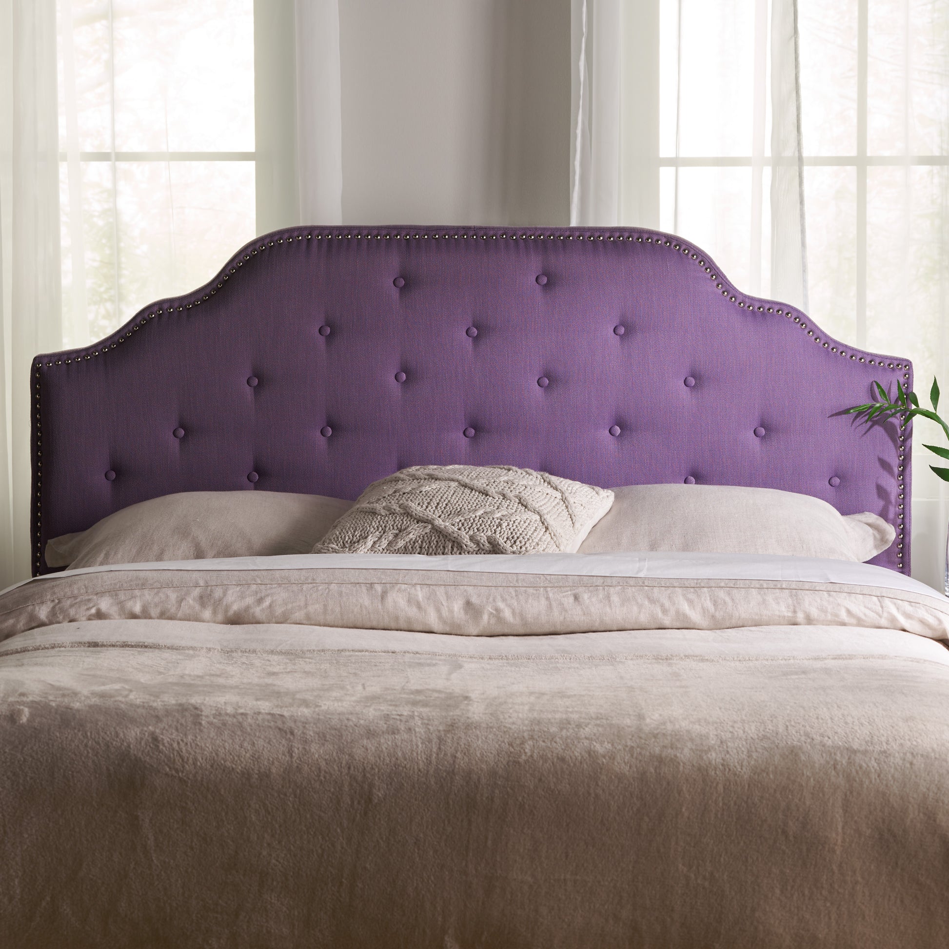 Tufted purple fabric headboard with nailhead trim