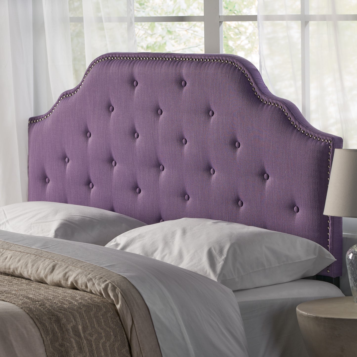Deep purple tufted headboard with silver nailhead trim and scalloped edge for a luxurious bedroom