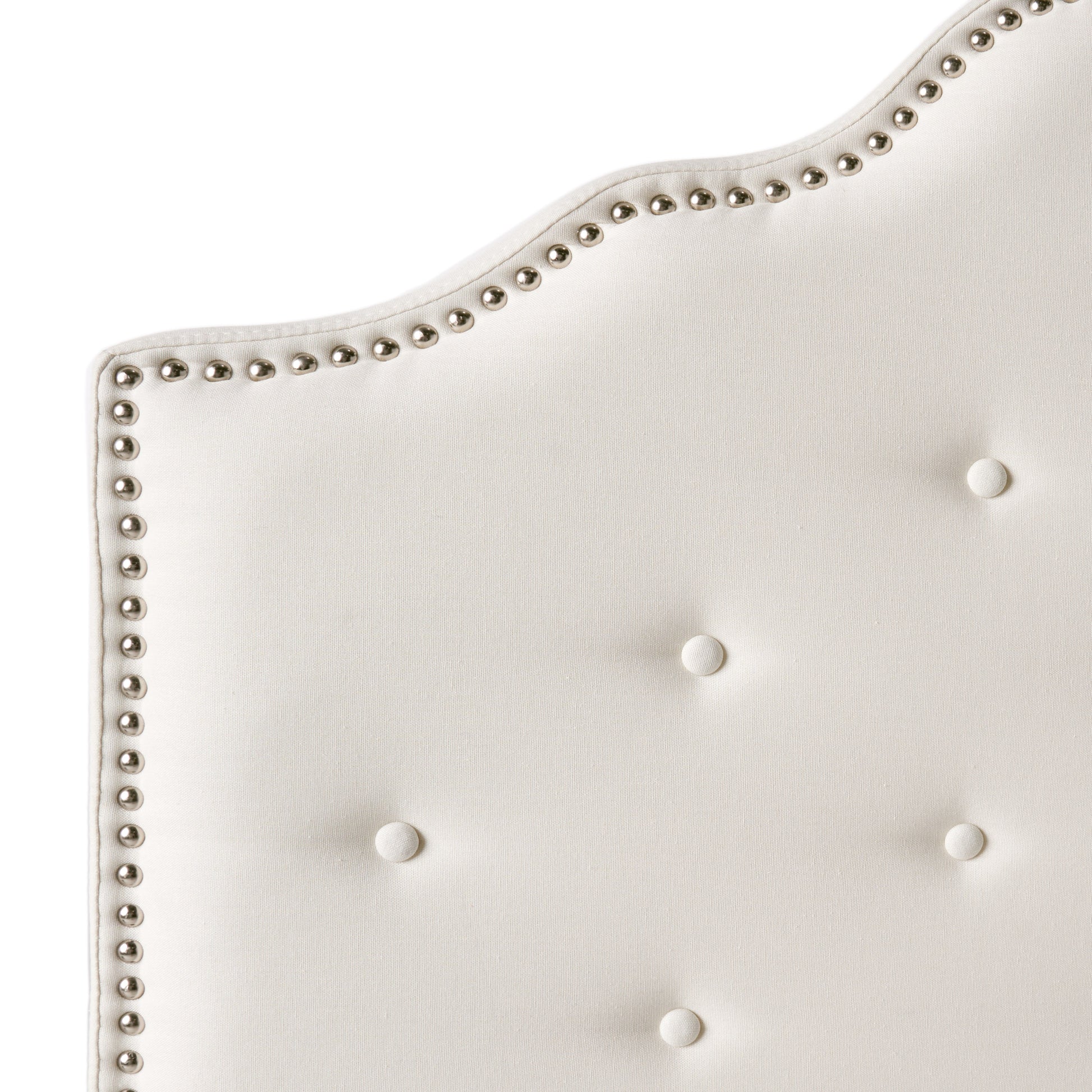 Cream tufted headboard detail with silver nailhead trim