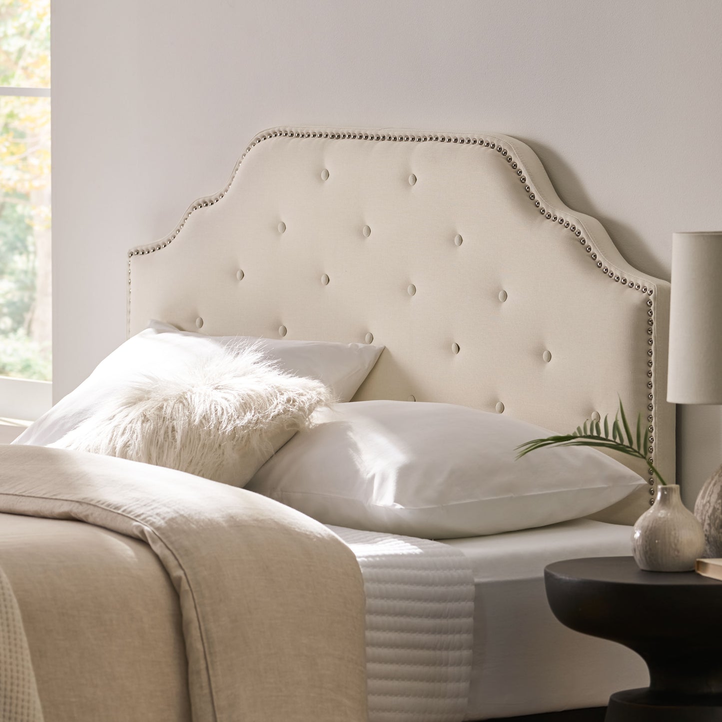 Cream fabric tufted headboard with nailhead trim accent