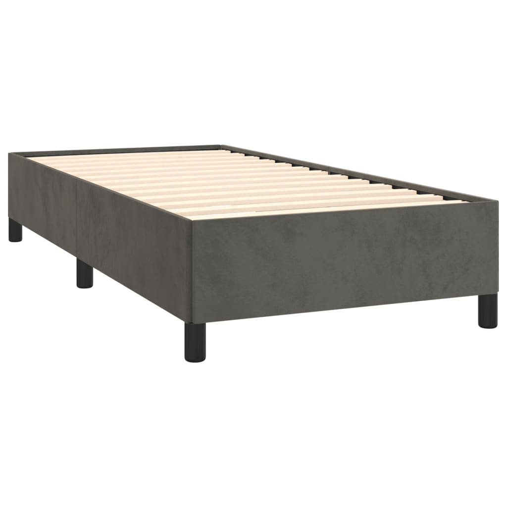 Gray upholstered twin bed frame with white bedding and a dark throw blanket