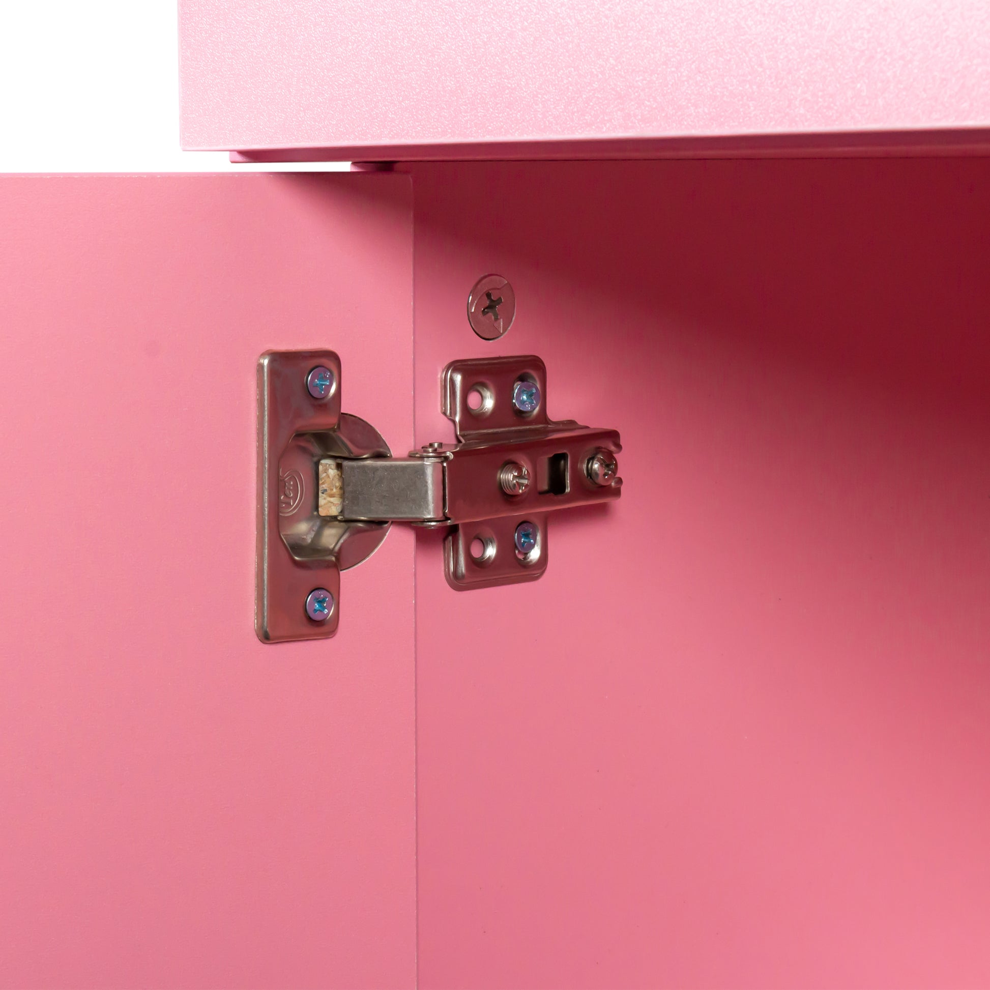 Closeup of a metal cabinet hinge with blue screws on a pink MDF door