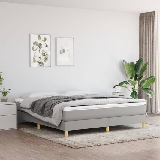 Gray upholstered divan bed with a thick white mattress and gray throw blanket