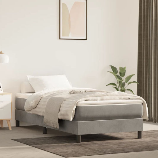Grey upholstered single bed frame with white bedding and throw blanket
