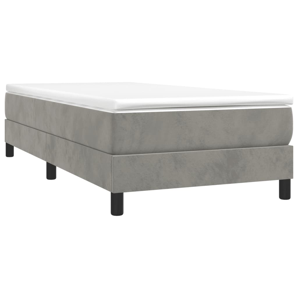 Grey upholstered divan bed with white mattress and black legs