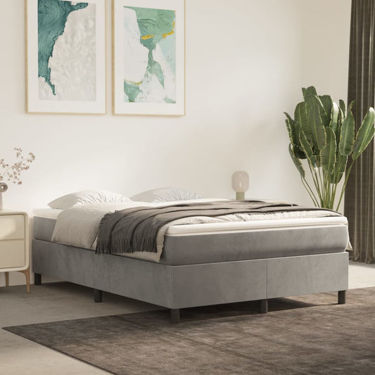 A grey upholstered divan bed with a white mattress and grey throw