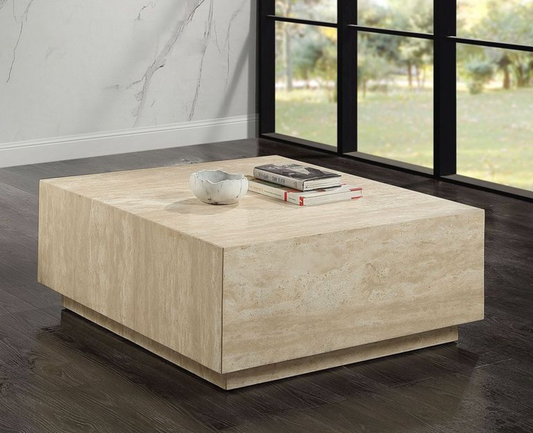 Beige travertine coffee table with stacked books and decorative bowl