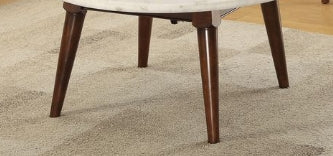 A round marble top coffee table with four tapered dark wood legs