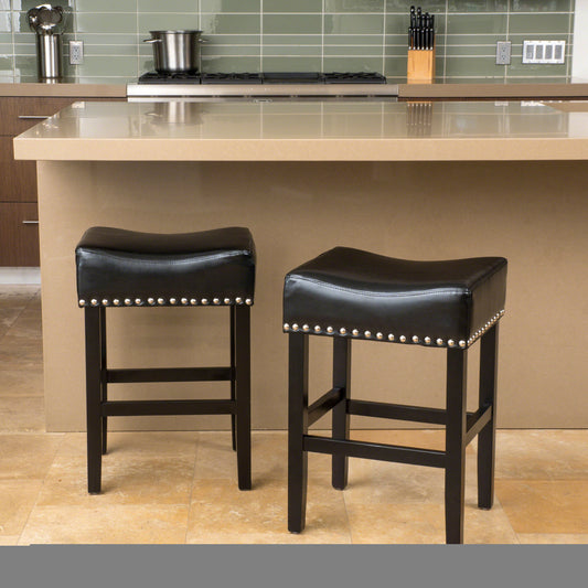 Pair of black faux leather bar stools with silver nailhead trim and dark wood legs