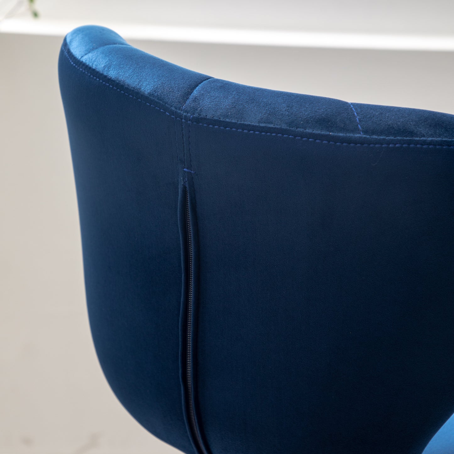 Navy blue velvet chair back with decorative stitching and a hidden zipper closure