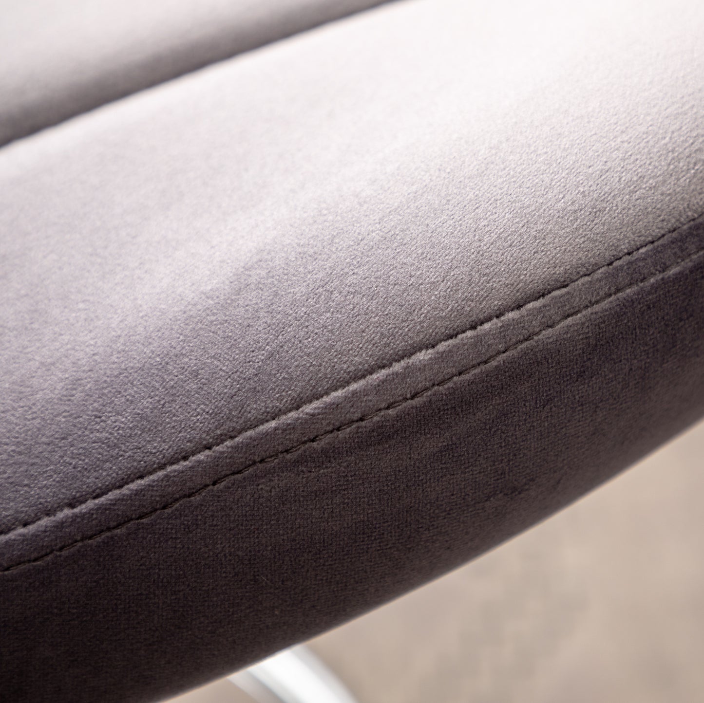 Closeup of dark grey velvet fabric texture with detailed stitching on a chair cushion