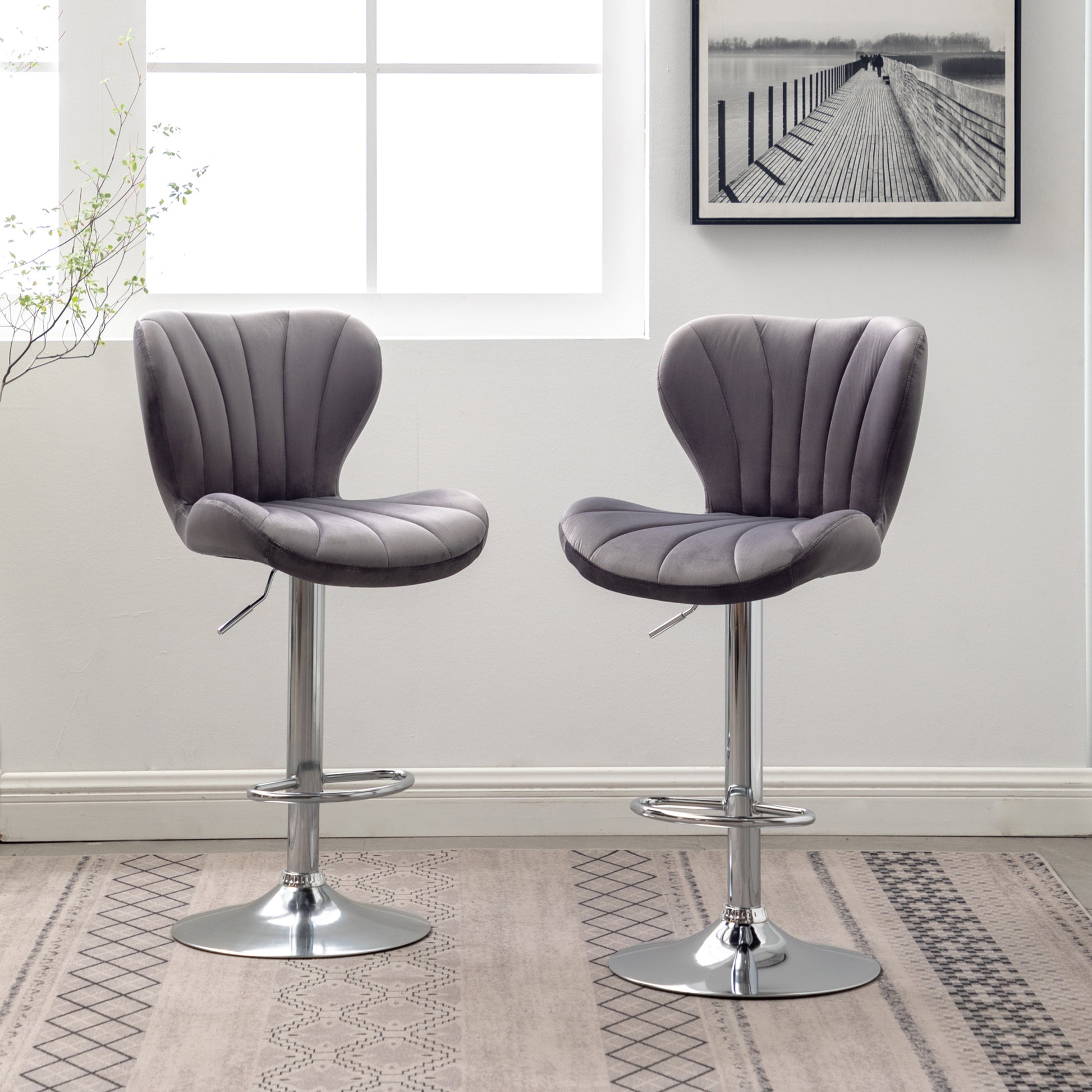 Two grey velvet bar stools with tufted backs and chrome bases