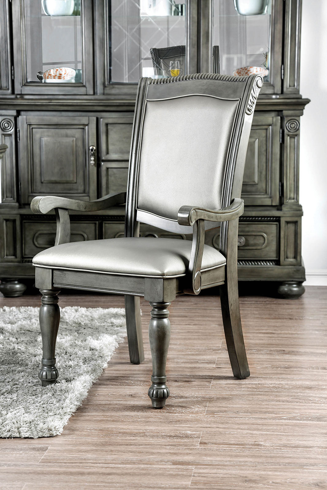 Grey upholstered arm chair with carved wooden details