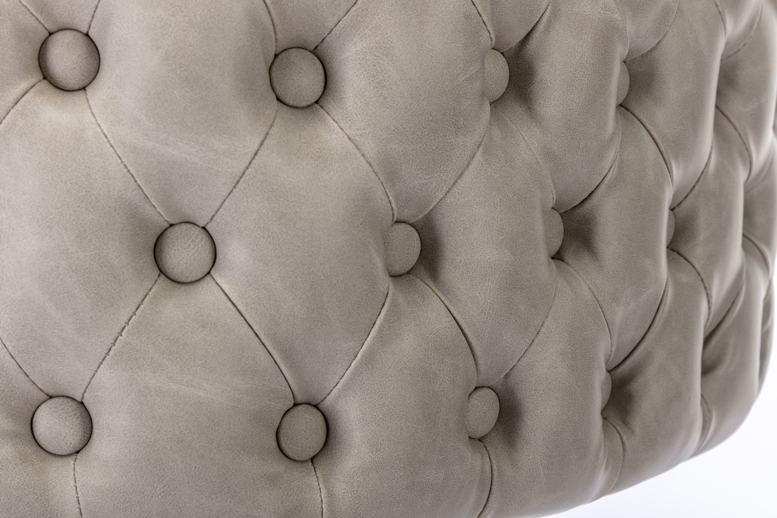 Closeup of gray tufted leather ottoman with button details