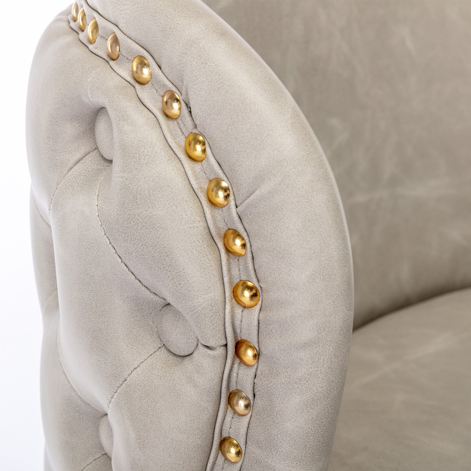 Light gray tufted armchair with gold nailhead trim
