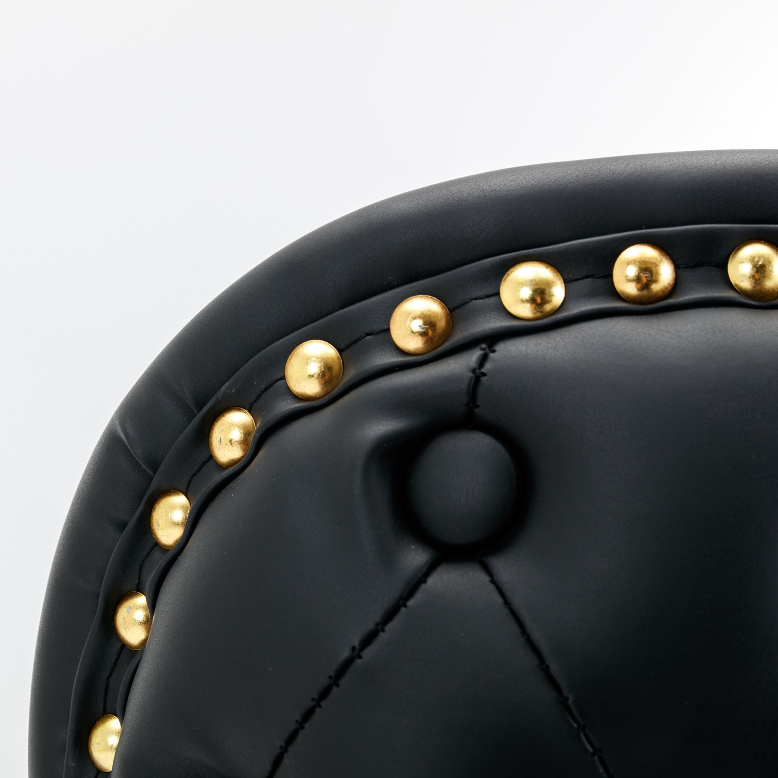 Black leather armchair detail with gold nailhead trim