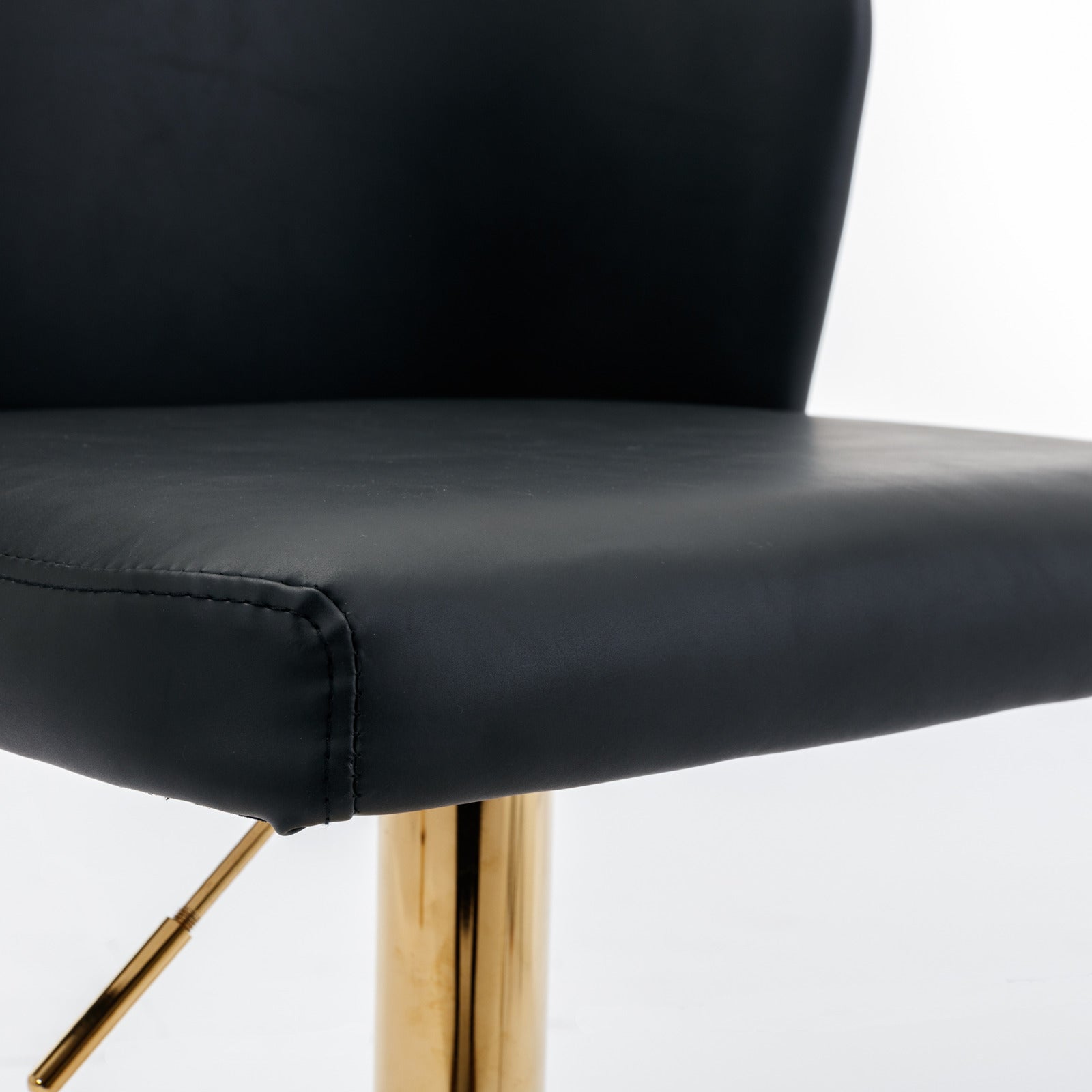 Black leatherette bar stool seat with detailed stitching and a polished gold adjustable base