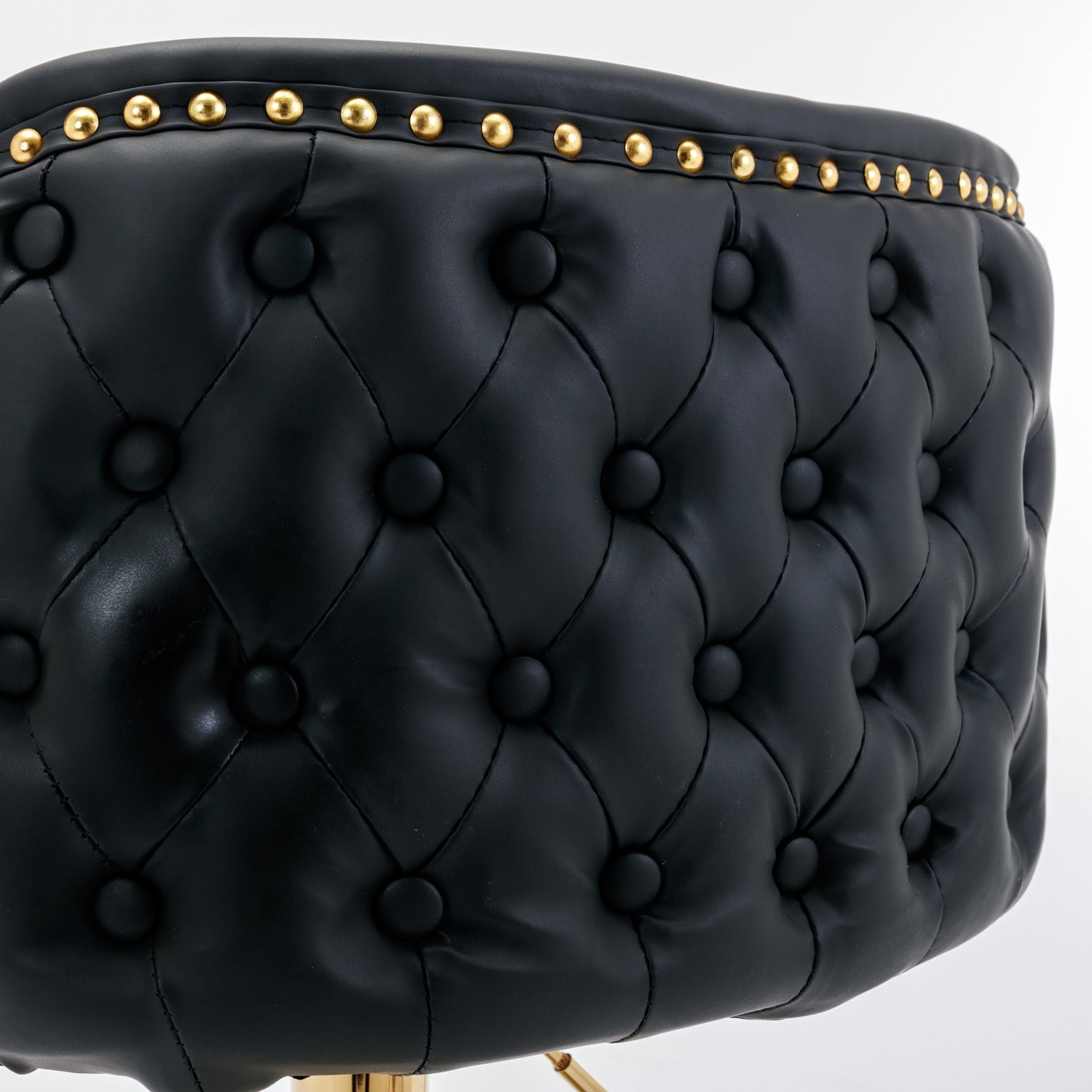 Tufted black faux leather stool seat with gold nailhead trim detail