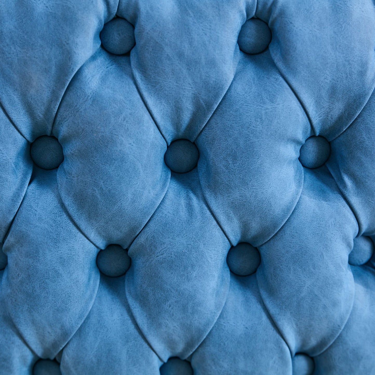 Closeup of tufted blue velvet upholstery with diamond stitching