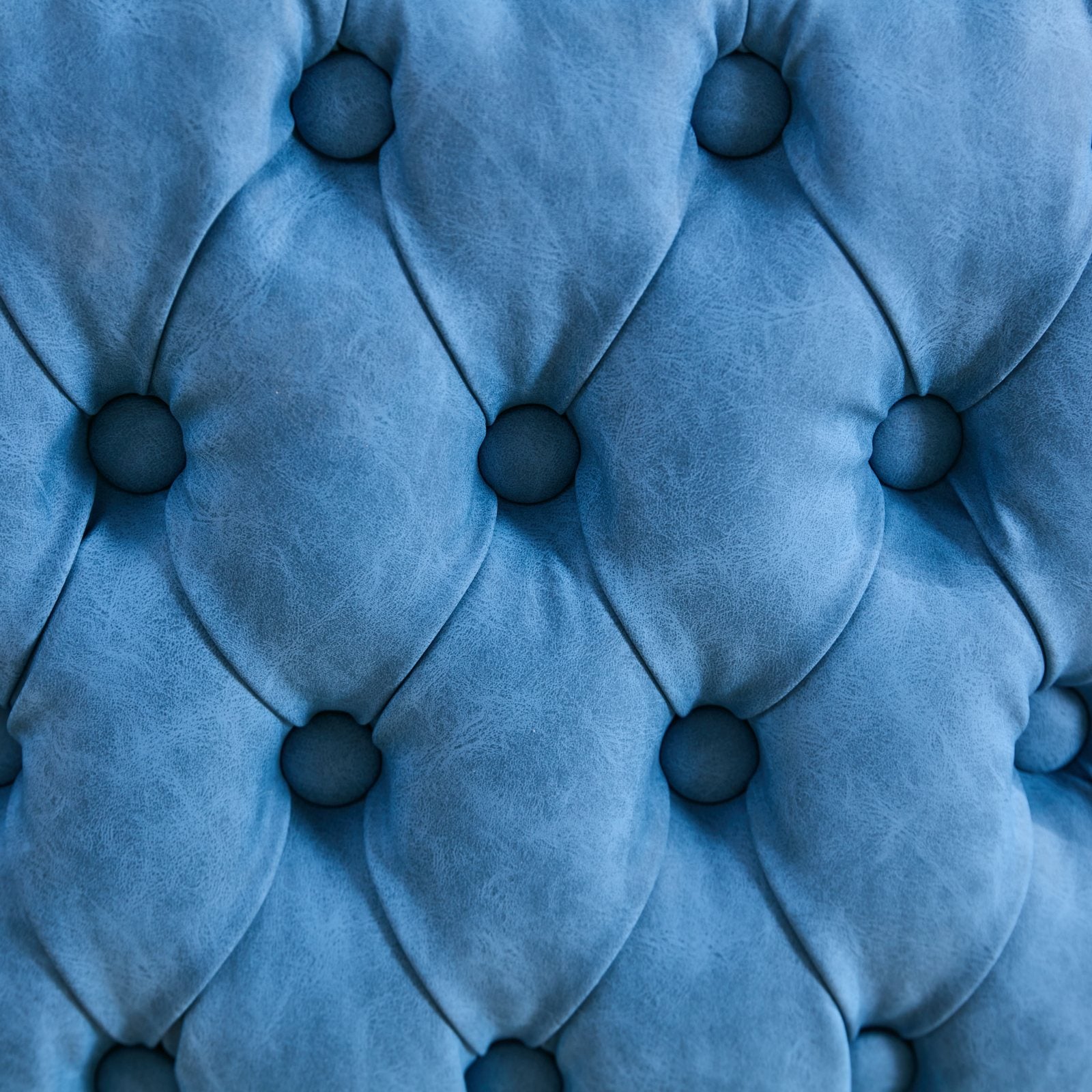 Closeup of tufted blue velvet upholstery with diamond stitching