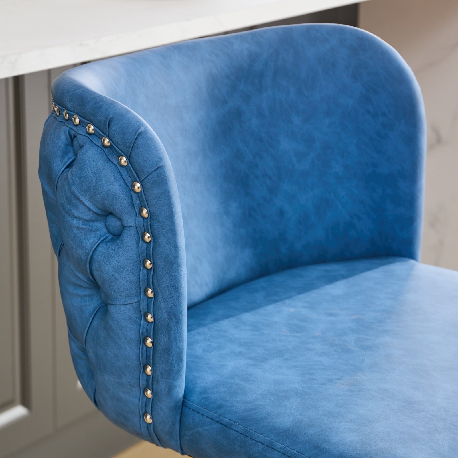 Blue tufted faux leather bar stool with gold nailhead trim