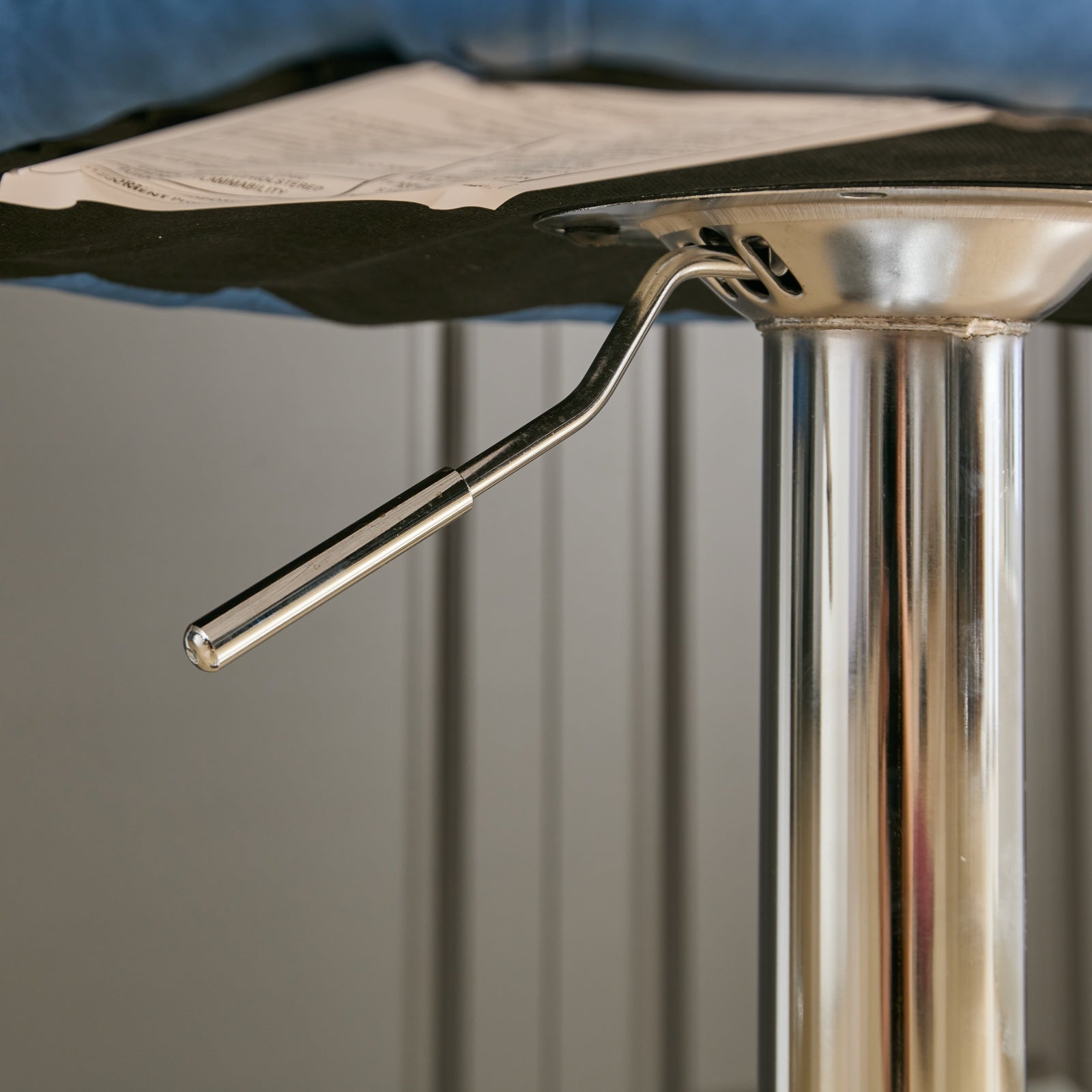 Closeup of shiny chrome gas lift lever on an adjustable bar stool