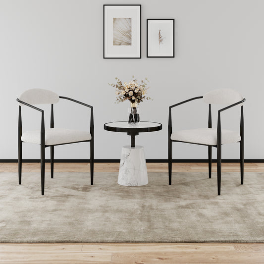 Cream boucle accent chairs with black metal frames flanking a marble side table with floral arrangement