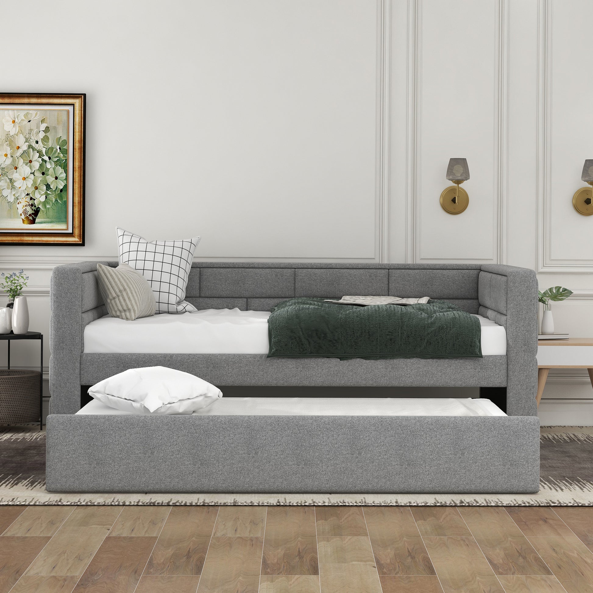 Gray upholstered daybed with trundle featuring tufted backrest and plush bedding