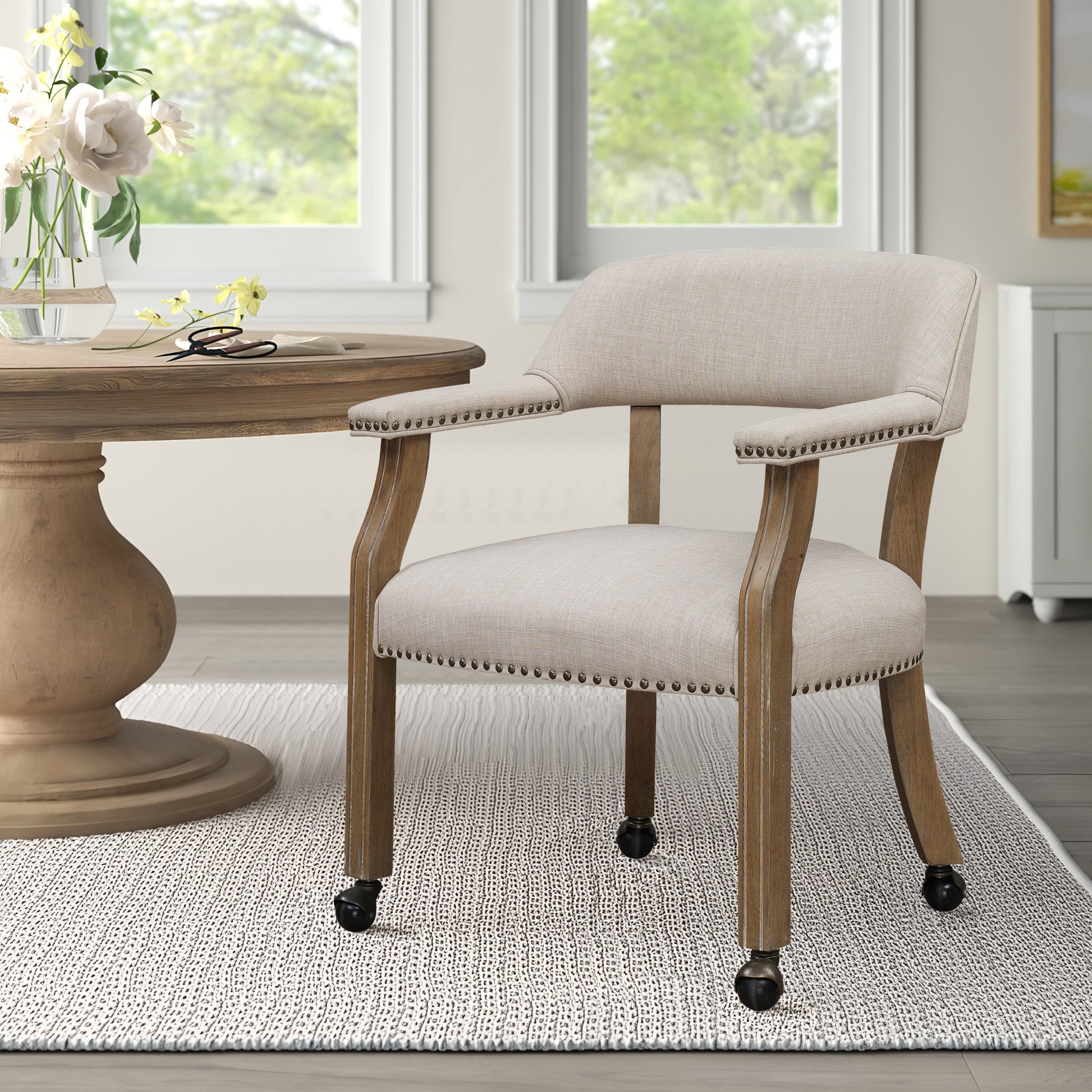 Beige upholstered accent chair with nailhead trim and casters
