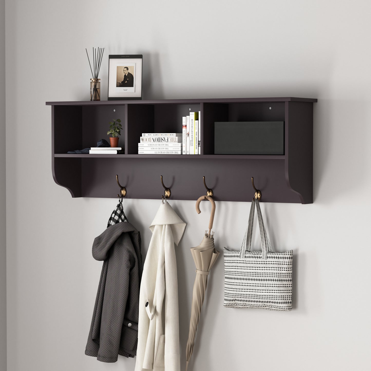 Dark wood entryway shelf with brass hooks holding coats umbrella and tote bag