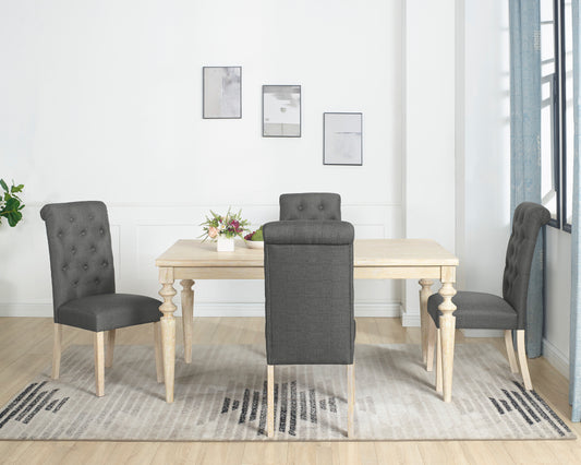 Dark grey tufted dining chairs with carved wood legs surrounding a light wood table