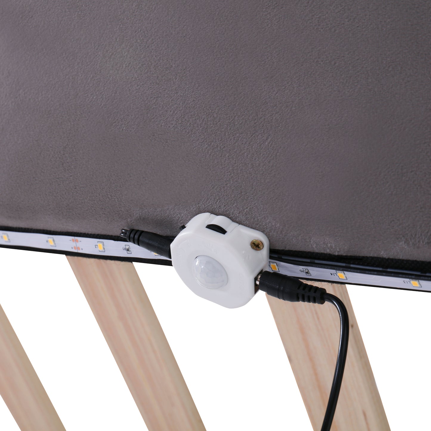 Motion sensor unit attached to LED strip lighting under a bed frame
