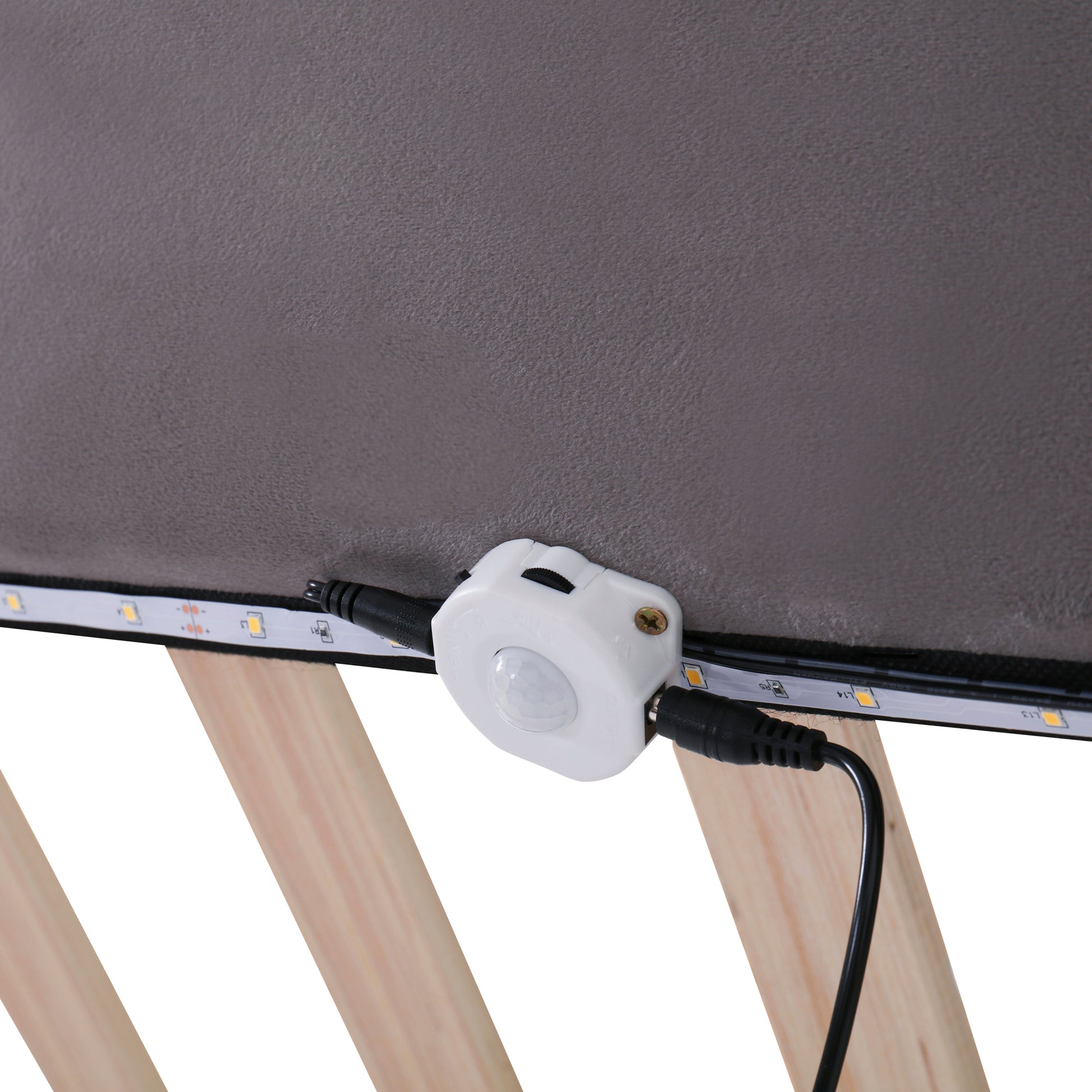 Motion sensor unit attached to LED strip lighting under a bed frame