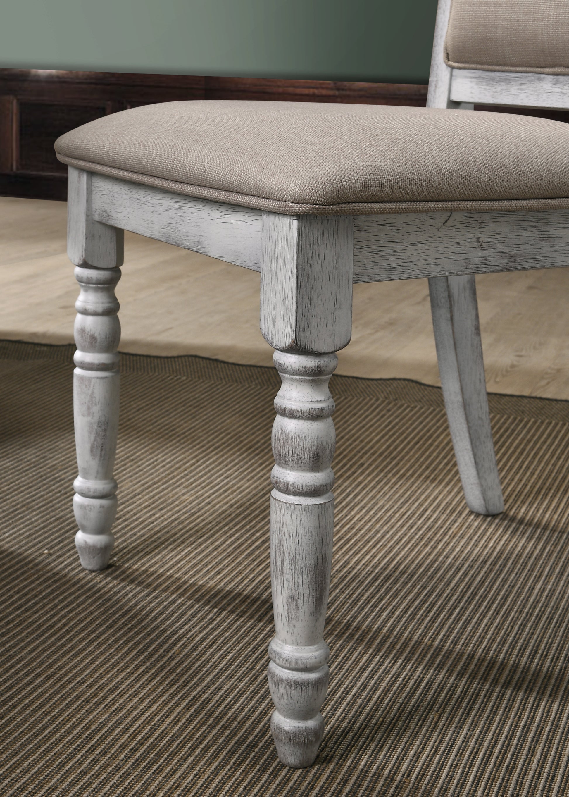 Closeup of distressed white wooden chair leg with carved details