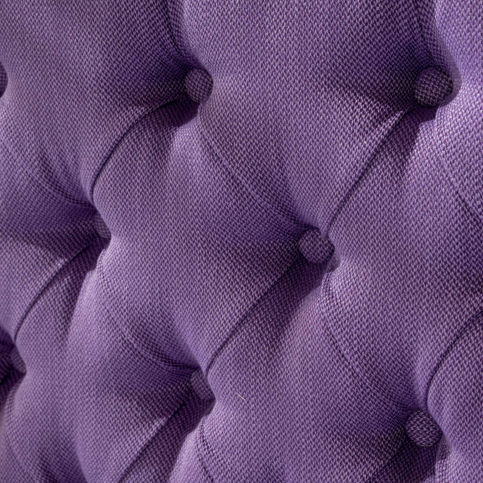 Tufted purple upholstered fabric showing diamond pattern and button detail