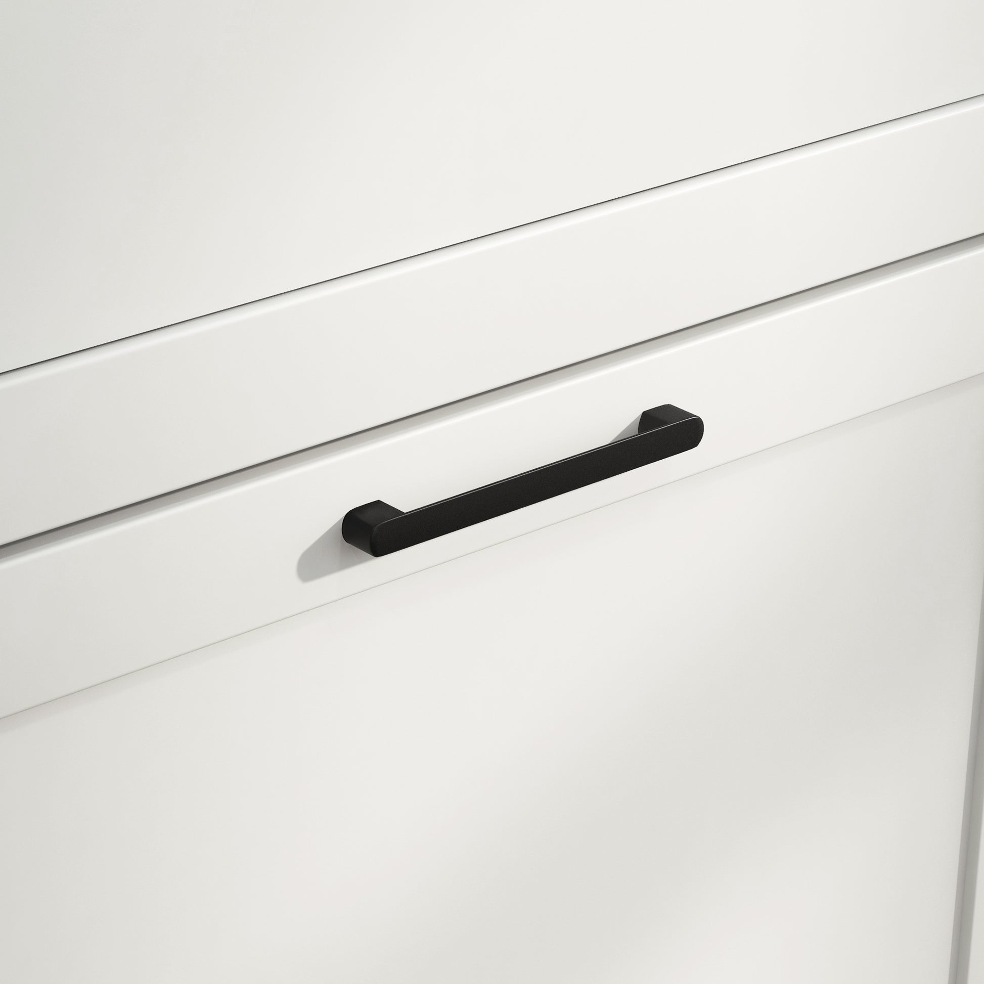 Matte black modern cabinet pull with clean lines on white drawer