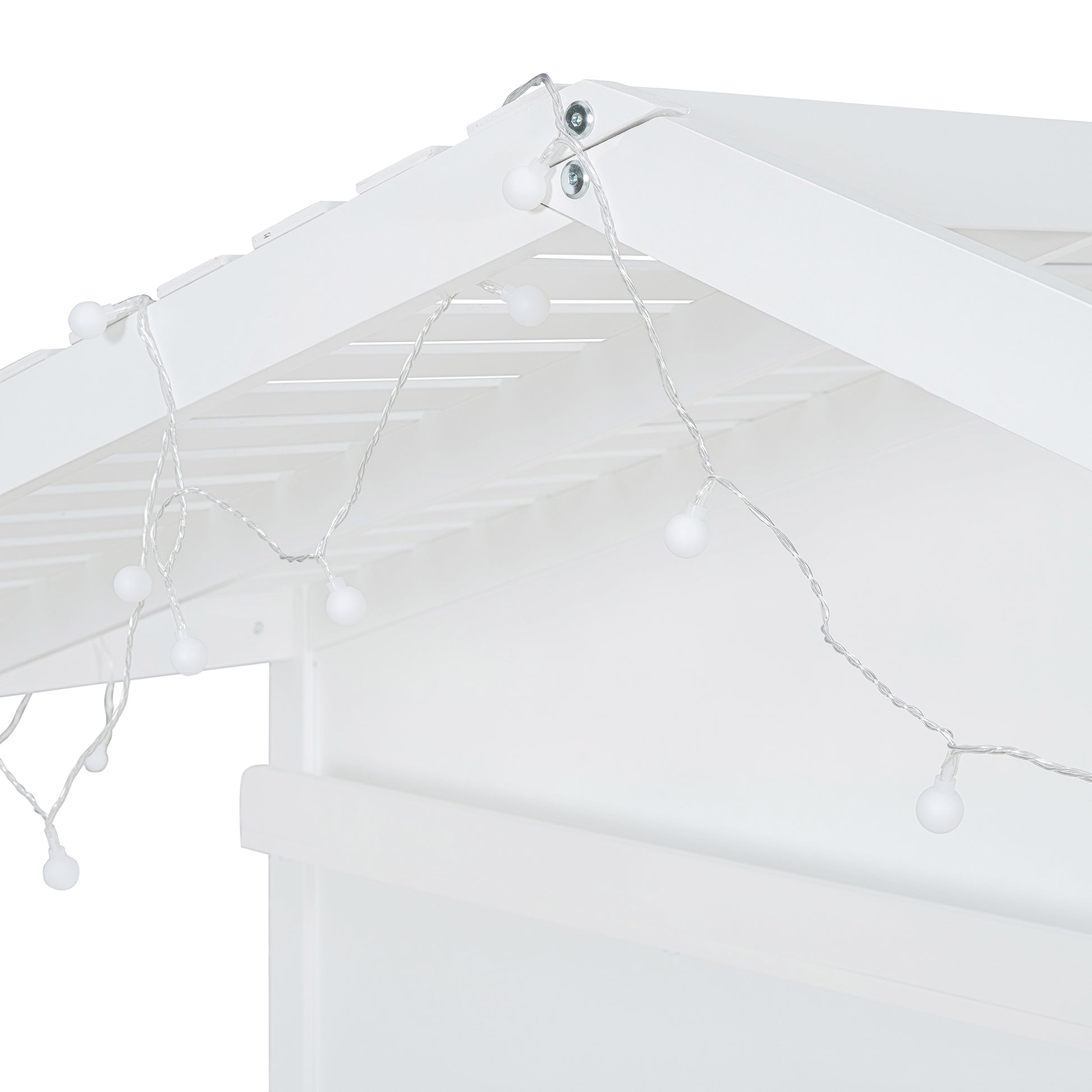 White string lights with round bulbs draped on a white wooden playhouse roof