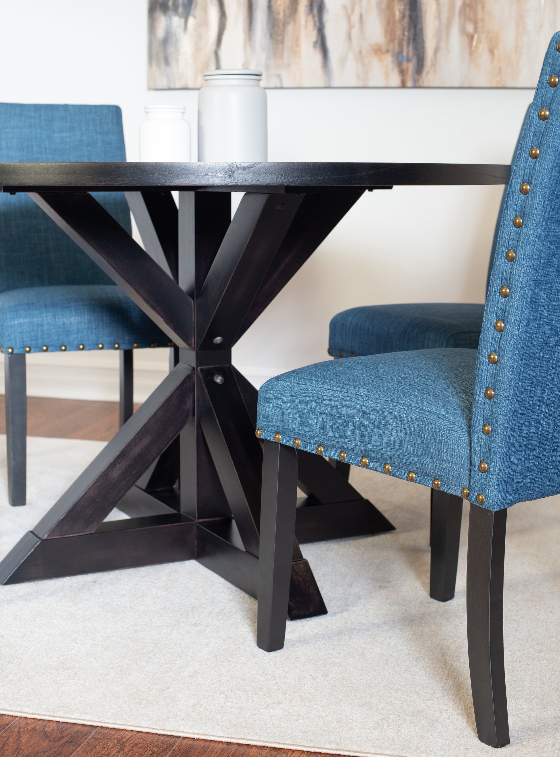 Dark wood dining table with Xleg base paired with upholstered blue dining chairs